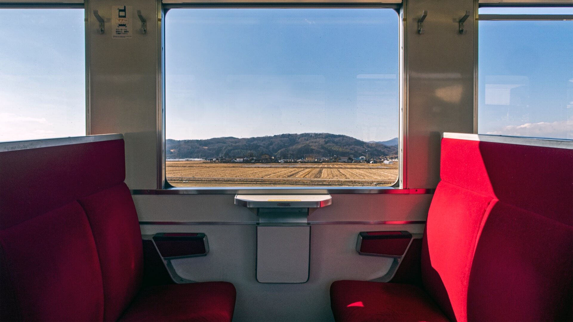 電車の窓から見える田園と山の景色