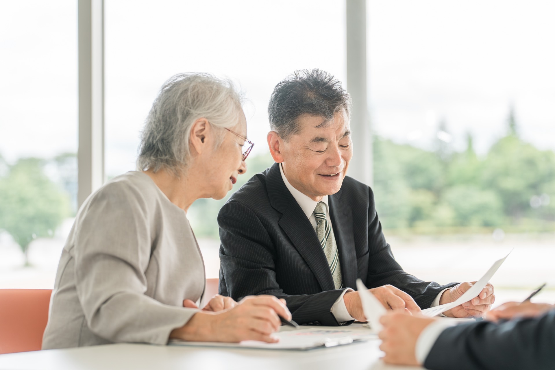 明るい部屋で、提案された書類を見ながら相談を受ける高齢の夫婦